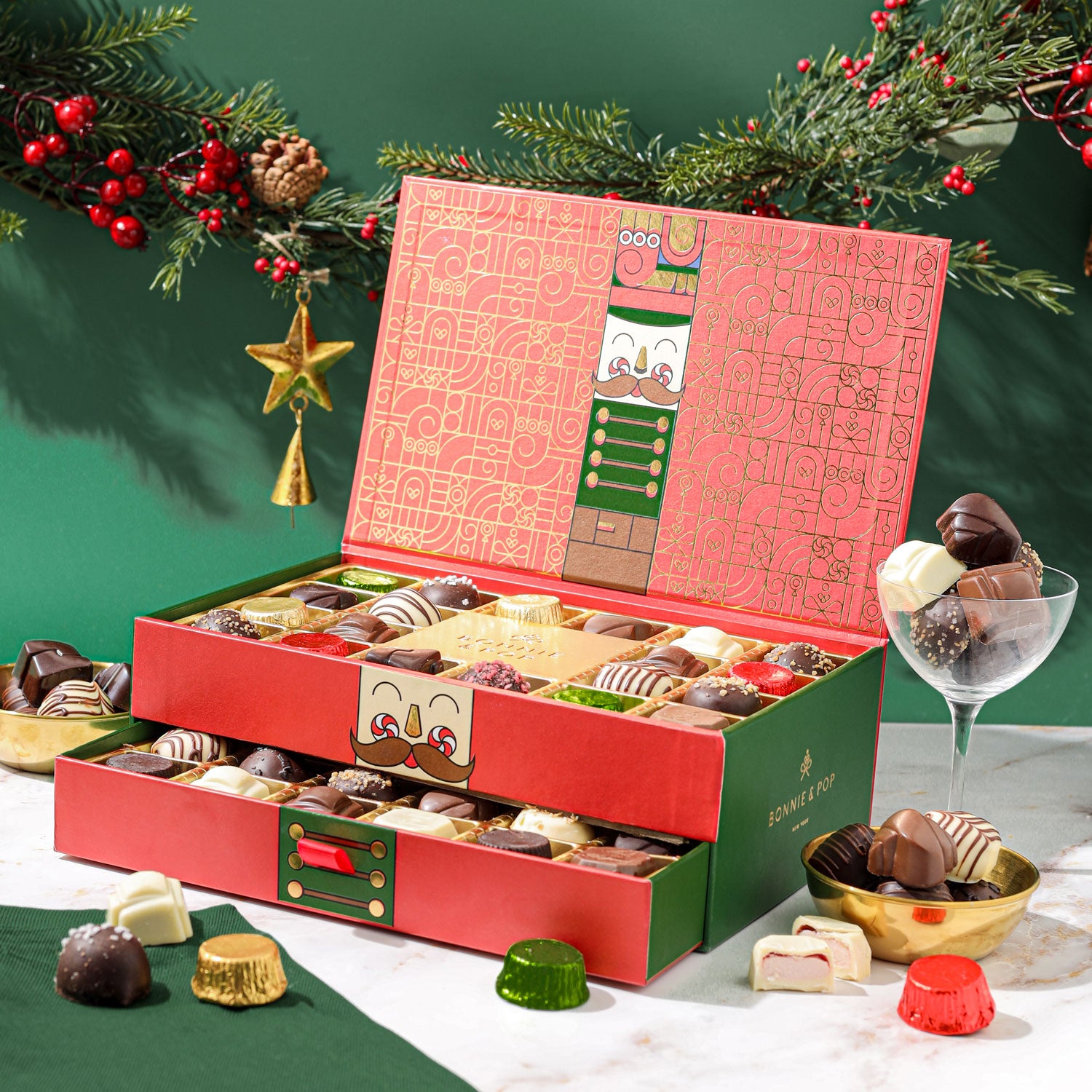 This Christmas Chocolate Truffle Gift Box open to reveal a variety of gourmet chocolate truffles inside. The box is red with green accents and has a decorative design.
